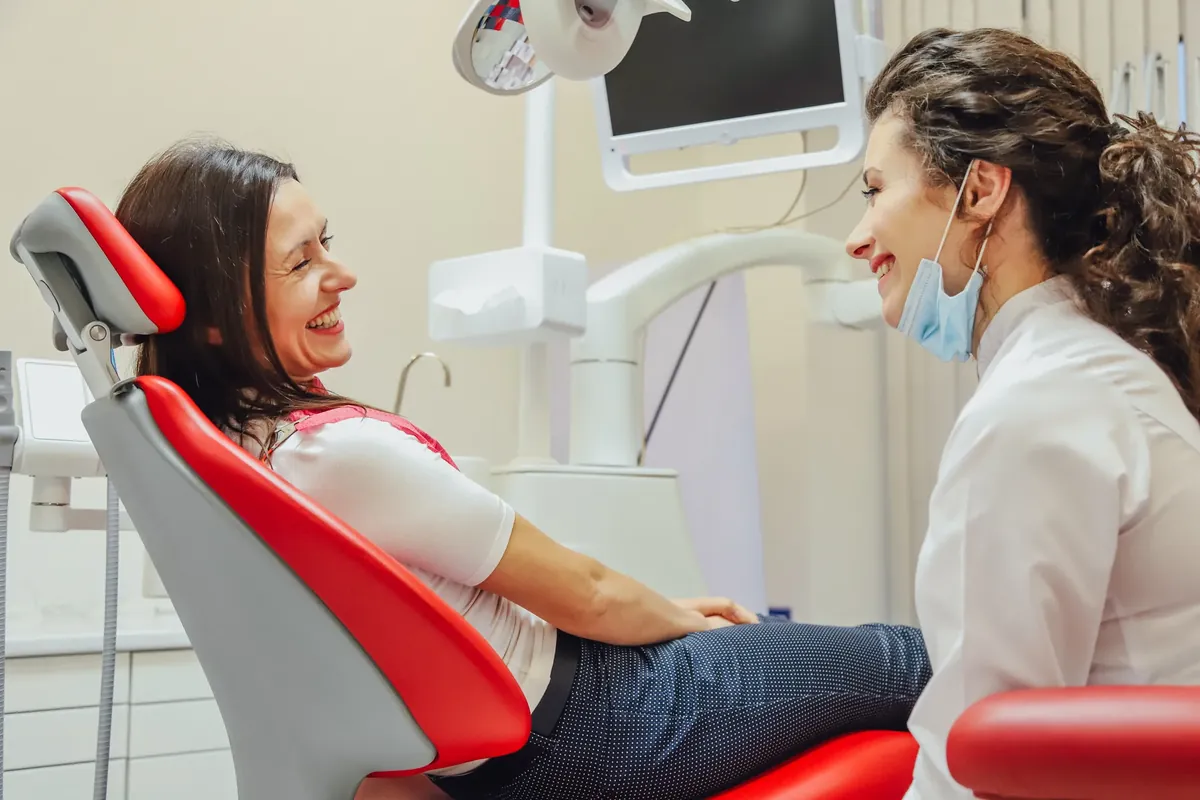 A patient laughing with her dentist in the dental chair